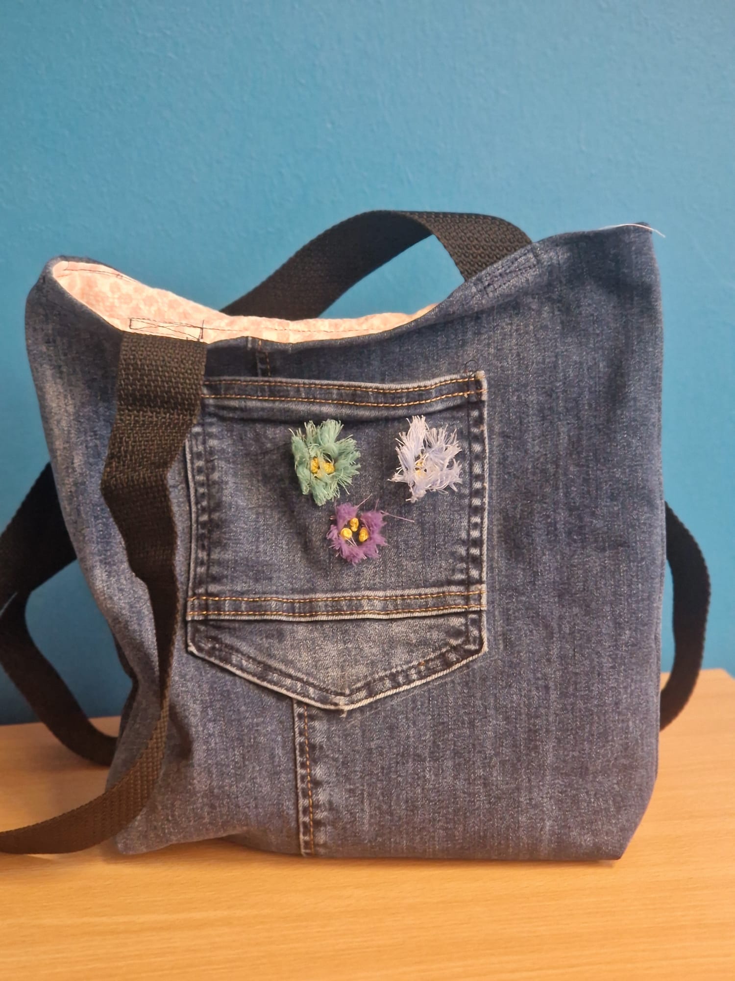 Tasche aus Jeansstoff mit schwarzem Tragegurt und blütenförmigen Stickereien