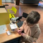 Ein Kind, das an einem Mikroskop arbeitet.