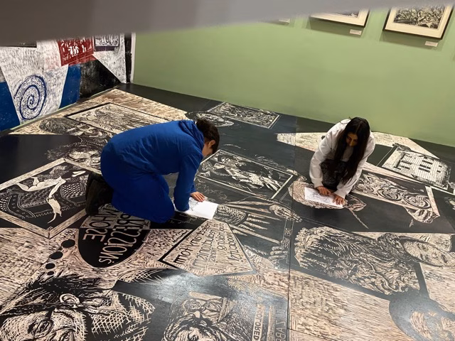 Eine Schülerin und ein Schüler sitzen auf dem Boden in einem Ausstellungsraum der Bremer Kunsthalle und zeichnen.