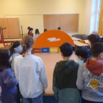 Eine Schülergruppe steht an einem Shuffle Board der Bremer Stadtreinigung.