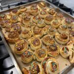 Ein Backblech voller Zimtschnecken mit Deko obendrauf.