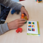 Ein Schüler baut nach Anleitung einen Würfel aus verschiedenen bunten Teilen zusammen.