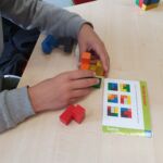 Ein Schüler baut nach Anleitung einen Würfel aus verschiedenen bunten Teilen zusammen.