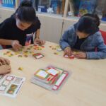 Schülerinnen versuchen ein Muster aus verschiedenen Puzzleteilen zulegen.