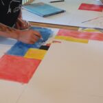 Ein Kind erstellt ein Kunstwerb, angelehnt an das Bild „Äquivalenz an den Horizontalen“ von Camille Graeser.