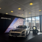 Ein schwarz-weißer Mercedes AMG. Daneben sind 4 Reifen gestapelt.