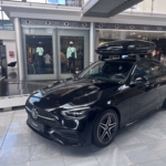 Ein schwarze C-Klasse mit einer Dachbox steht im Kundencenter