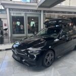 Ein schwarze C-Klasse mit einer Dachbox steht im Kundencenter