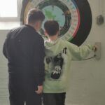 Zwei Schüler stehen vor einem Ausstellungstück. Dies ist rund mit viel Text.