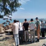 Eine Schülergruppe steht auf einem Berg und schaut von dort auf Malaga hinab. Es sind Häuser und das Meer zu sehen.