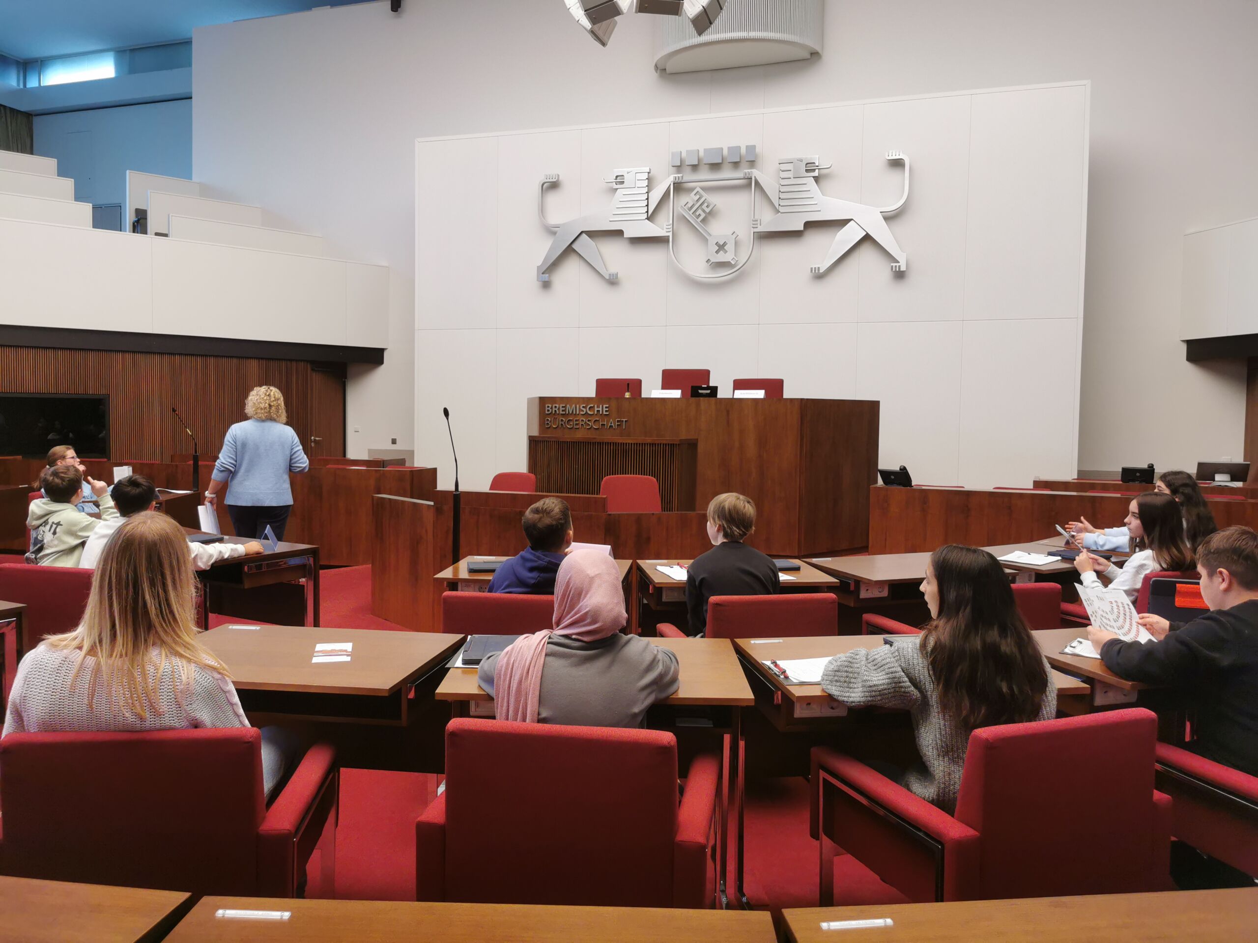 Schülerinnen und Schüler sitzen im Plenarsaal der Bremer Bürgerschaft auf den Plätzen der Abgeordneten.