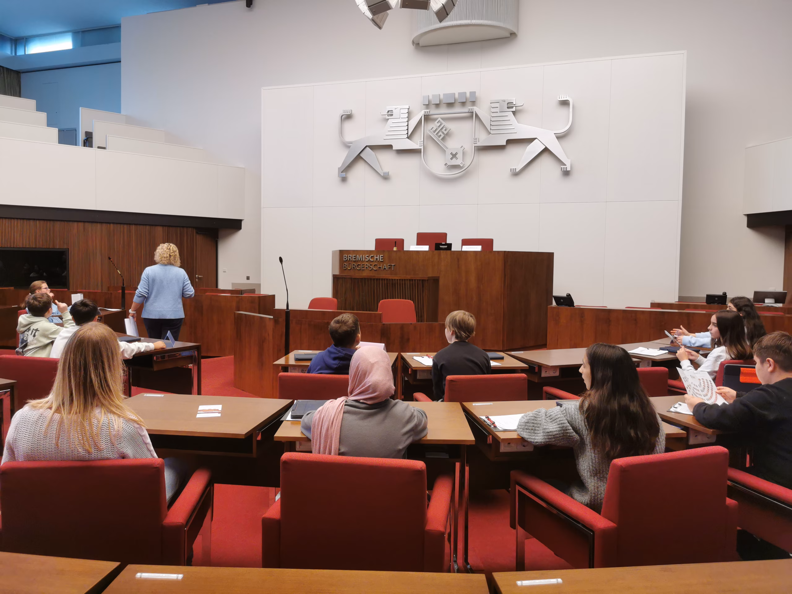 Schülerinnen und Schüler sitzen im Plenarsaal der Bremer Bürgerschaft auf den Plätzen der Abgeordneten.