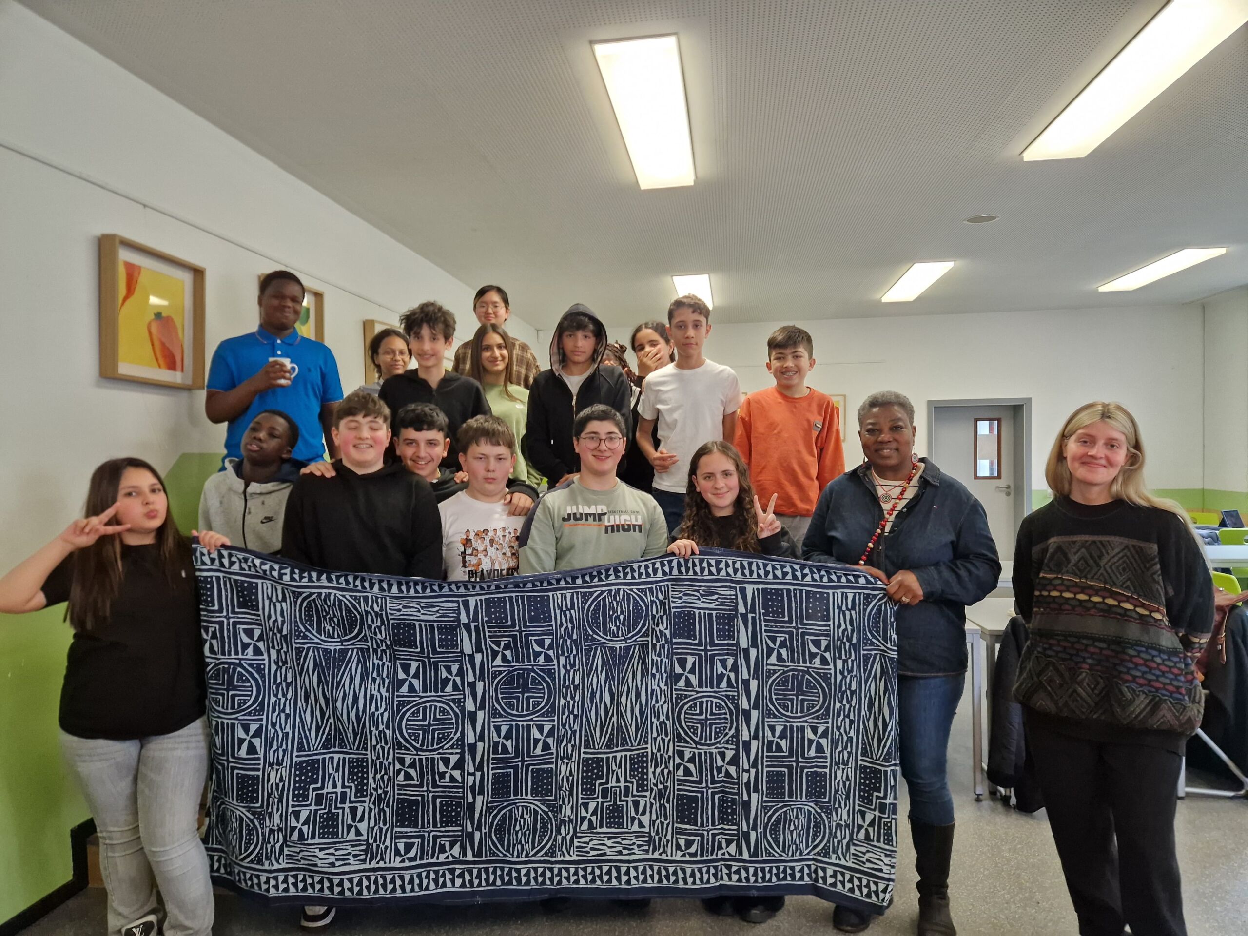 Eine Gruppe Schülerinnen und Schüler halten eine Decke mit schwarz-weißen Motiven hoch.
