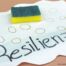 Ein Schwamm liegt auf einem Blatt Papier auf dem das Wort Resilienz steht.
